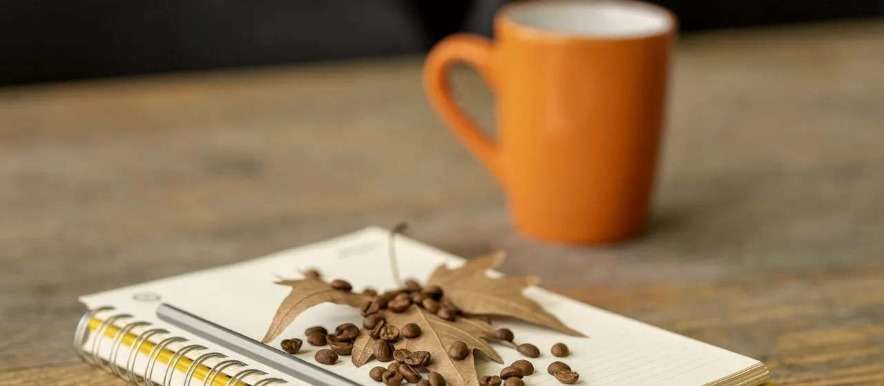 Un cuaderno y un café sobre una mesa de madera